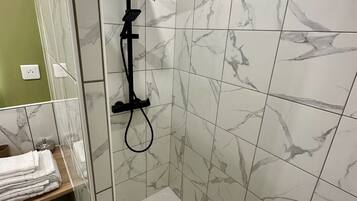 Une douche moderne dotée d’un pommeau de douche carré, d’un pommeau de douche à main et d’un panneau de commande.