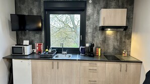 A compact kitchen with a microwave, toaster, sink, and cabinets.