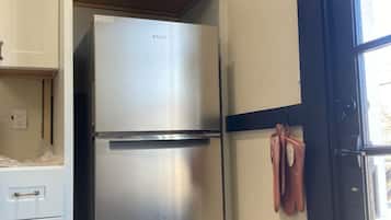 Una cocina con un refrigerador de acero inoxidable, gabinetes blancos y un marco de puerta negro.