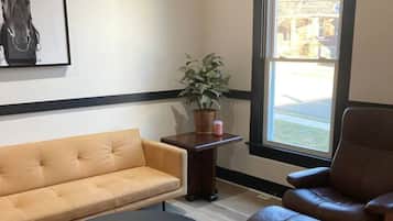 Una sala de estar con un sofá, dos sillones, una mesa de centro, una planta en maceta y una ventana con vistas.