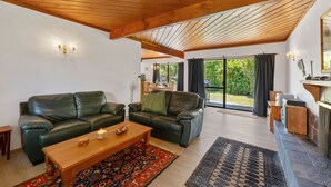 Amplia sala de estar con techo de madera, chimenea y vistas al exterior.