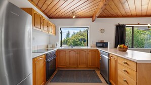Una cocina moderna con armarios de madera, electrodomésticos de acero inoxidable y vistas al exterior.