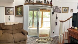 A living room with a brown armchair, a lamp, and a fireplace. There is a sliding glass door leading to a deck. - Majestic, three bedroom mountaintop vacation retreat! Pet friendly! (Topton)