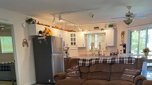 A modern living room with a brown sofa, a round coffee table with decorative items, and a kitchen in the background. - Majestic, three bedroom mountaintop vacation retreat! Pet friendly! (Topton)