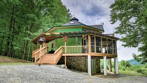 A two-story wooden cabin with a porch and a covered outdoor area, surrounded by forest. - Majestic, three bedroom mountaintop vacation retreat! Pet friendly! (Topton)