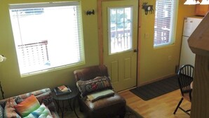 A living room with a sofa, a chair, a small table, and a door leading to another room. - Cabin on the Kenai River (Soldotna)