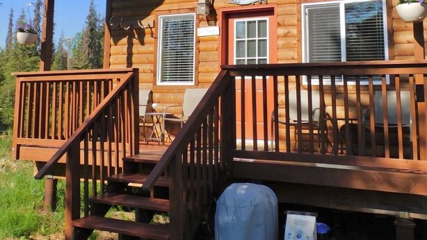 A wooden cabin with a porch, a covered grill, and a sign that reads "Redoubt." - Cabin on the Kenai River (Soldotna)