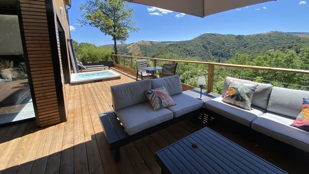 Una terraza de madera con un sofá, una mesa y un jacuzzi.