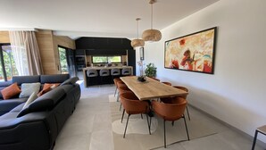 Una sala moderna con un sofá, una mesa de comedor y sillas. Hay una zona de cocina con un juego de comedor y un cuadro grande en la pared.