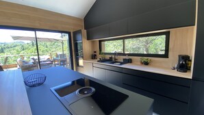 Una cocina moderna con un amplio ventanal, un lavamanos integrado y una cafetera.