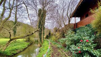 A garden with a narrow water channel, trees, and a wooden building.