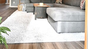 A cozy living room with a gray sectional sofa, a wooden ceiling, and a white shag rug. - Waterfront house on Miner Lake- Waupaca Chain (Waupaca)