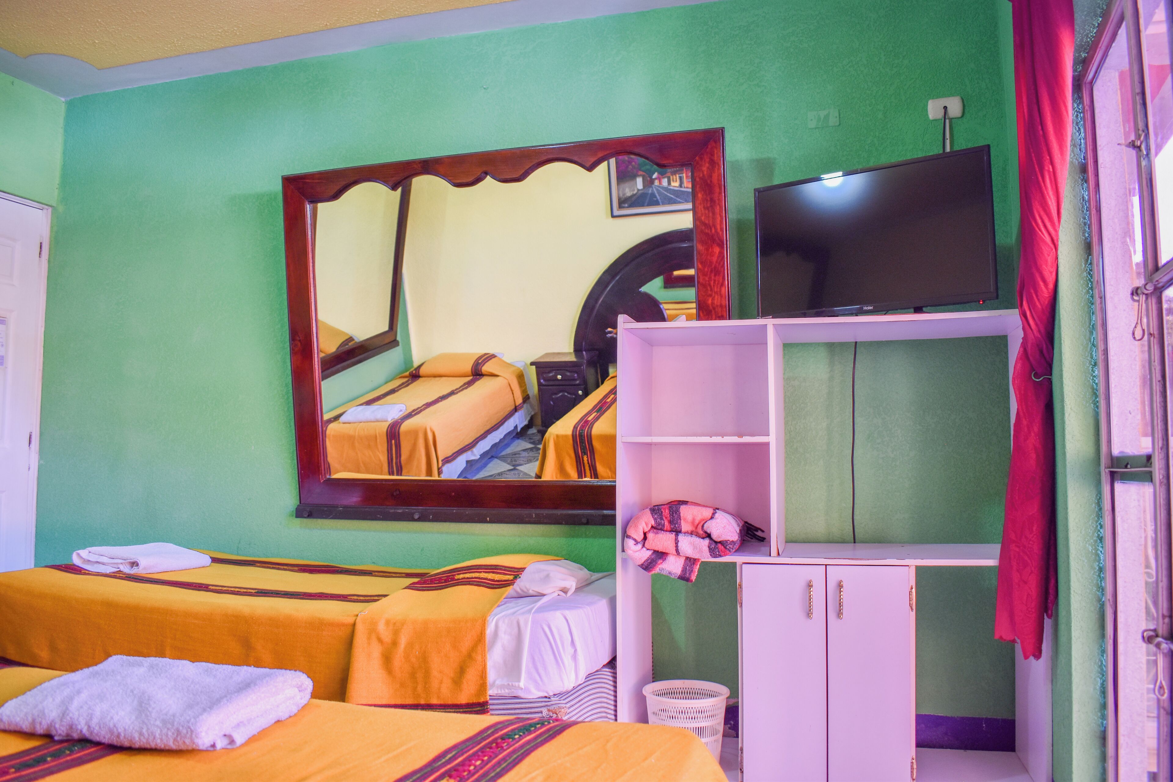 Une chambre avec deux lits, une télévision, un miroir et une armoire.