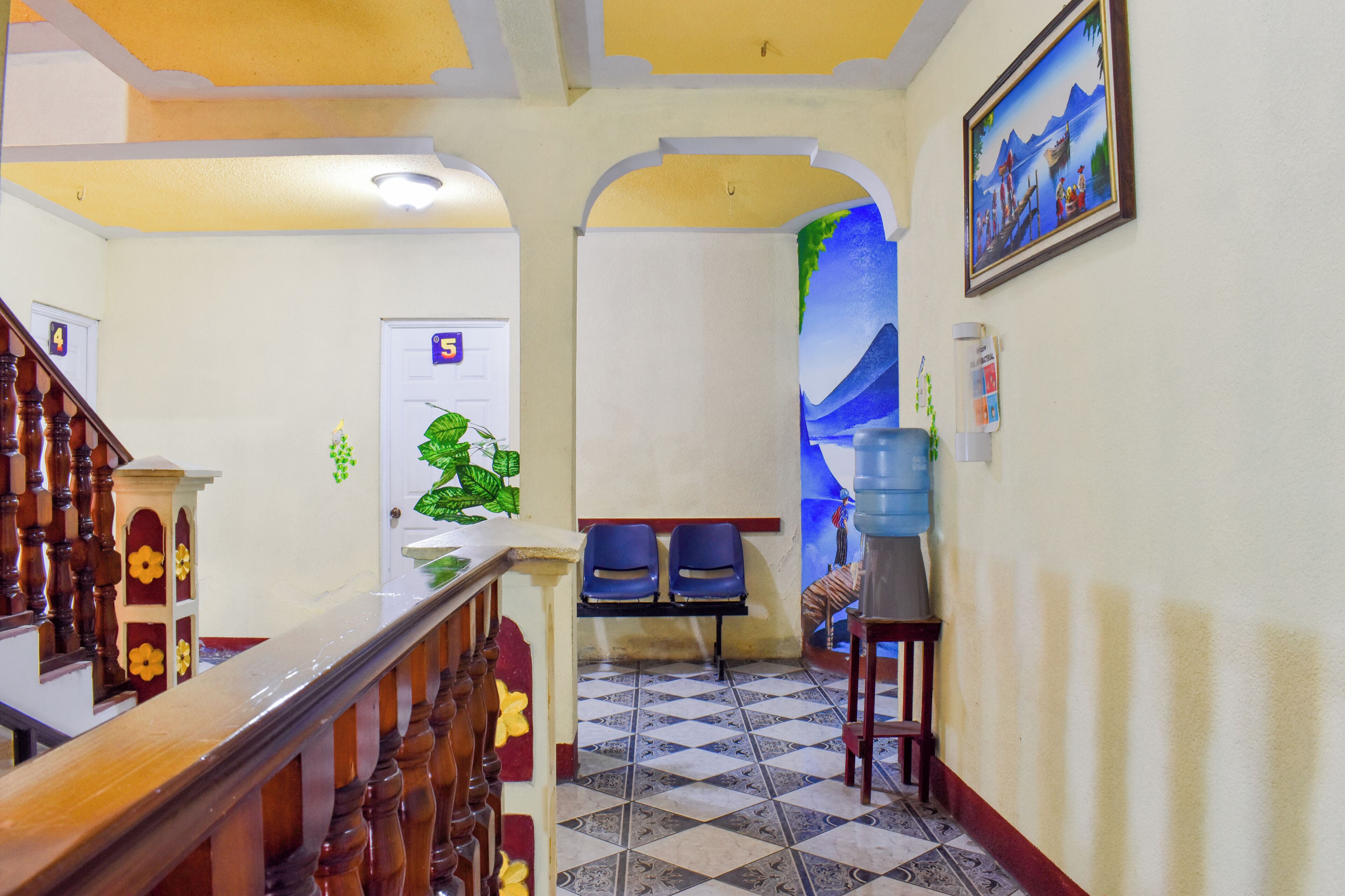 Un pasillo de hotel con una escalera, un dispensador de agua y una puerta marcada con el número 5.