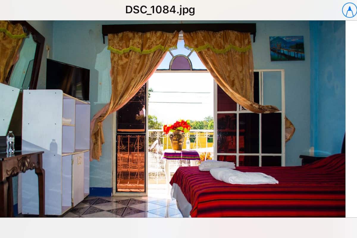 A room with a bed, a desk, and a window with curtains.