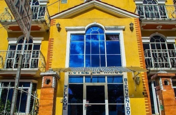 A yellow building with a large arched window and a sign that reads "WELCOME". - Hotel el Amigo (Panajachel)