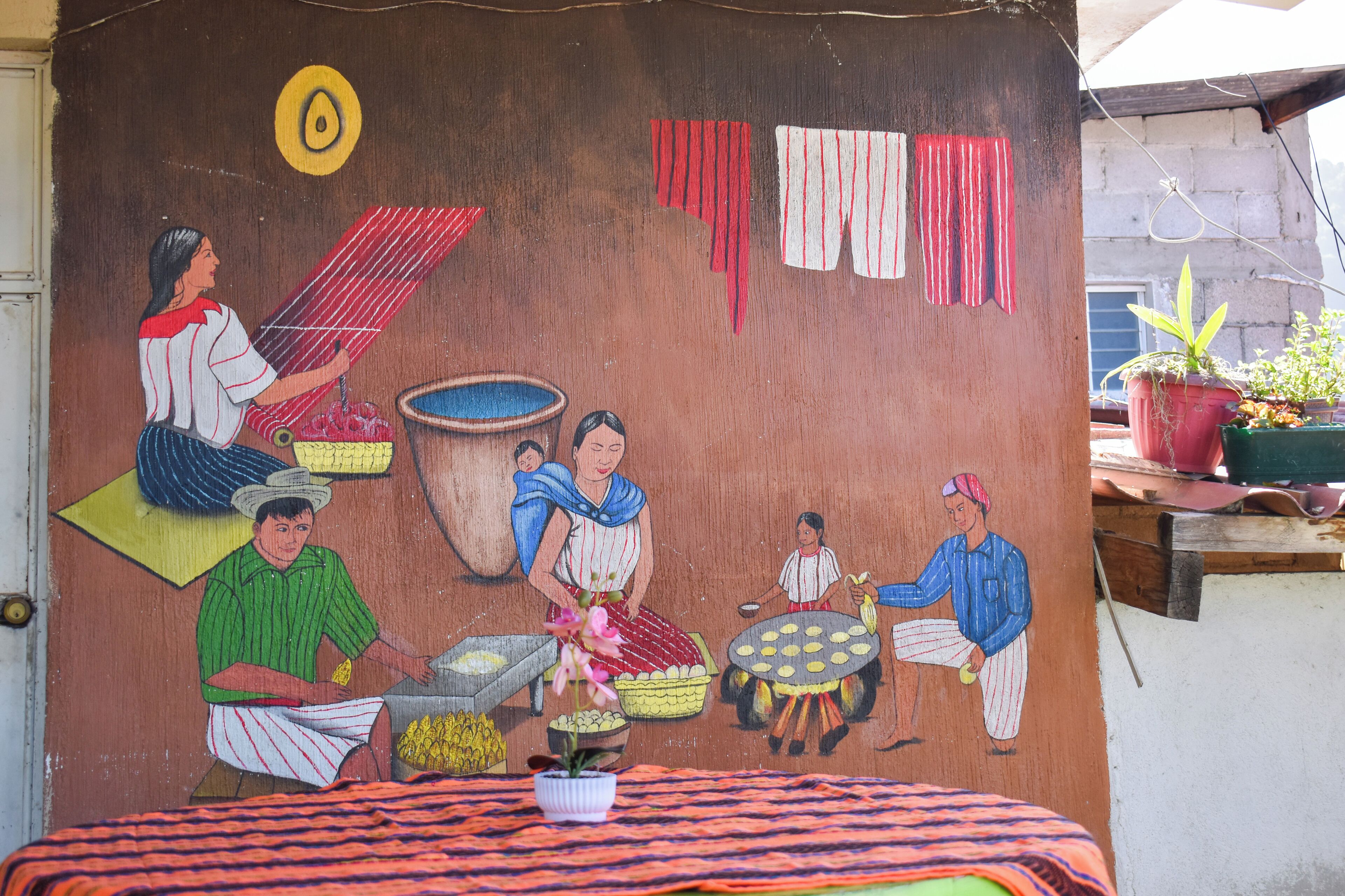 A mural depicting a traditional scene with people engaged in various activities, such as cooking and washing clothes.