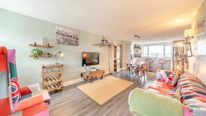 A living room with a sofa, a coffee table, a TV, and a dining area with chairs and a table. - 2 bedroom accommodation in Quebec (Quebec)