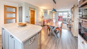 A modern kitchen with a central island, built-in appliances, and a dining area with a long table and chairs. - 2 bedroom accommodation in Quebec (Quebec)