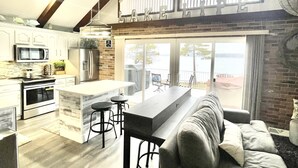A spacious kitchen with modern appliances, a dining area with a bar, and a cozy seating area with a view. - Lincoln Lake Paradise with Tiki Bar & Hot Tub (Gowen)