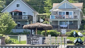 A waterfront property with a dock, outdoor seating, and a thatched umbrella. - Lincoln Lake Paradise with Tiki Bar & Hot Tub (Gowen)