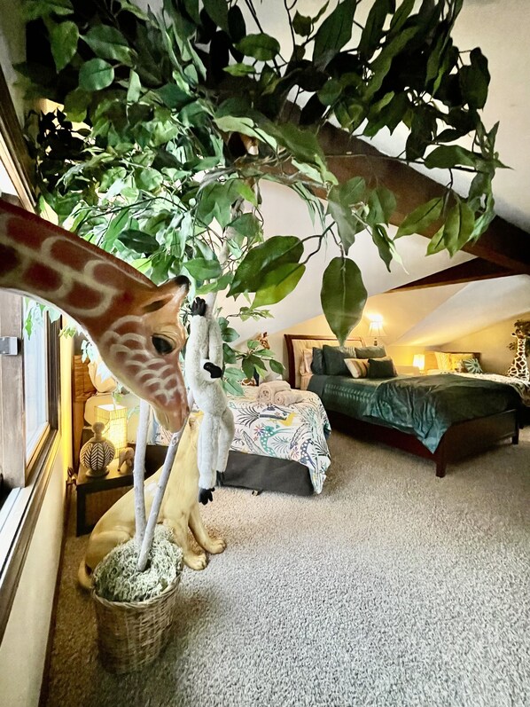 Une pièce comprenant un lit, un canapé et une statue de girafe.