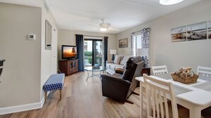 Uma sala de estar moderna com televisão, área de estar e mesa de jantar.