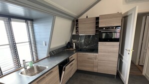 Una cucina moderna con forno integrato, lavastoviglie e un'ampia finestra con persiane.