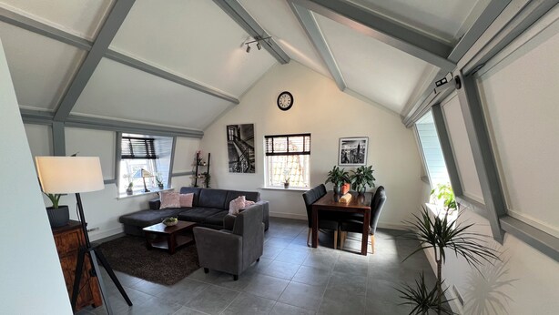Un loft spazioso con soffitto alto, zona pranzo, divano e piante in vaso.