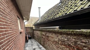 Un stretto vicolo con un muro in mattoni da un lato e un tetto in tegole dall'altro.