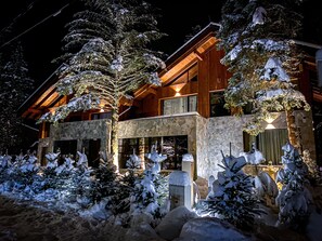 A large, multi-story wooden building with stone accents and snow-covered trees in front. - Jasna Boutique Chalet (Demanovska Dolina)