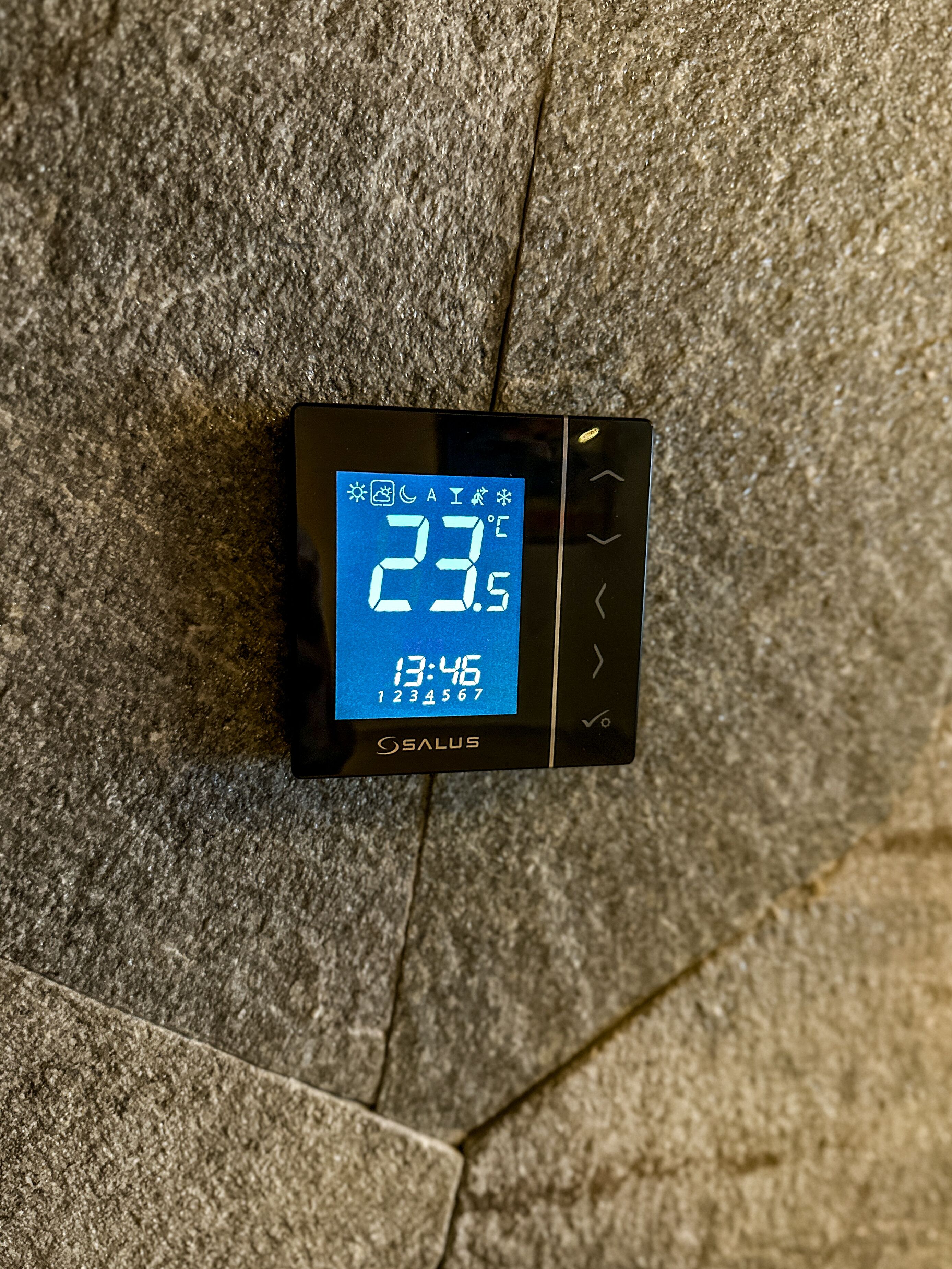 Termòstat digital que mostra una temperatura de 23,5 °C i l'hora 13:46.