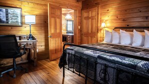 Quarto de cabana de madeira com cama, escrivaninha e cadeira.