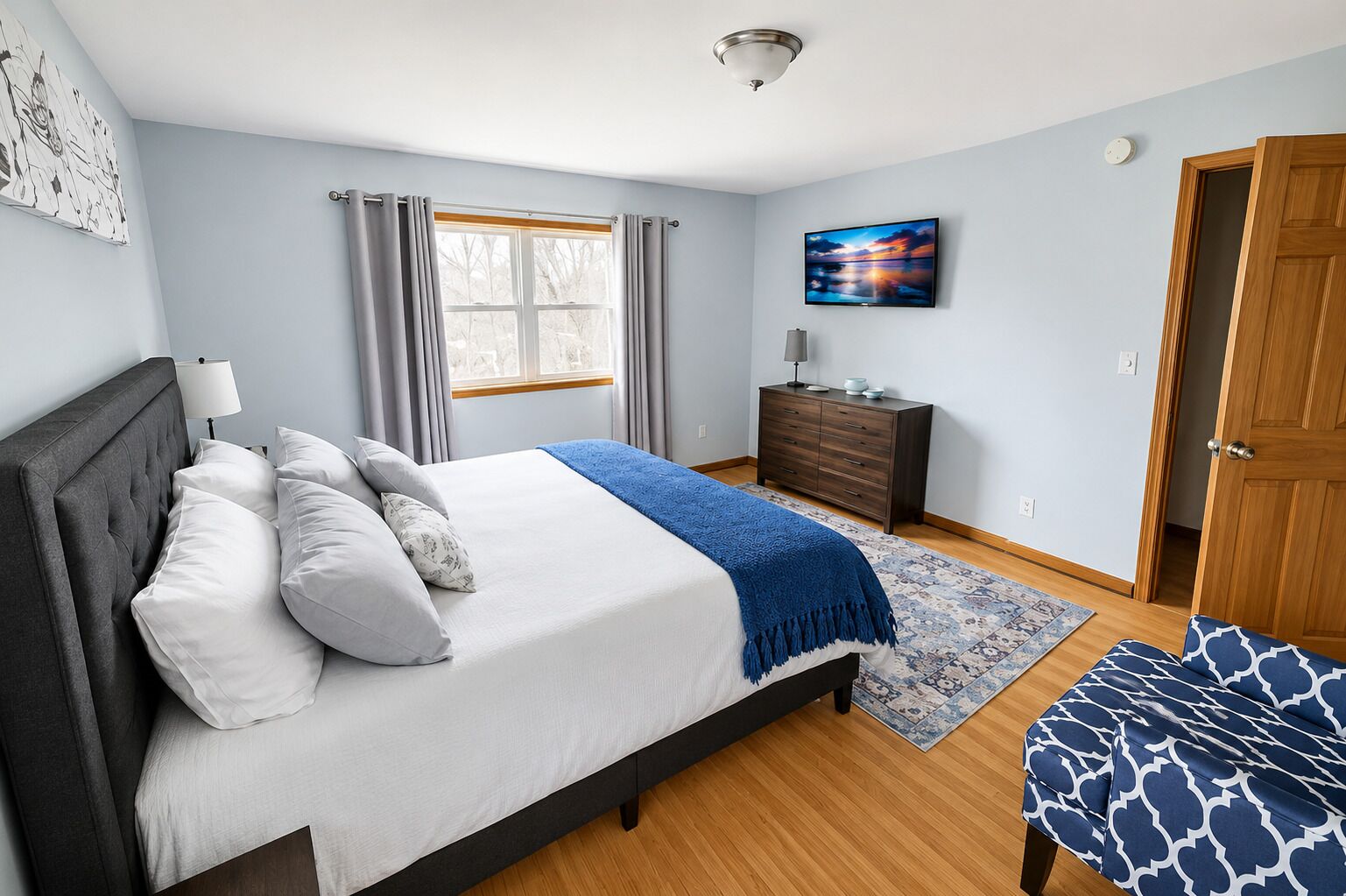 Un dormitorio con cama, cómoda, televisor y puerta.