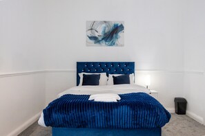 Une chambre à coucher avec un lit, une table de chevet, une lampe et un tableau au mur.
