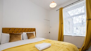 Een hotelkamer met een bed, een raam met gordijnen en een radiator.