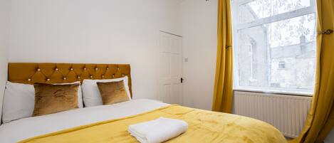 Una habitación de hotel con cama, ventana con cortinas y radiador.