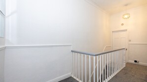 Een gang met witte wanden, een witte deur en een lamp aan het plafond.