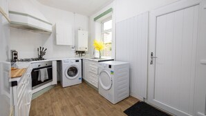 Een praktische keuken met een wasmachine, een kookplaat en een raam met uitzicht.