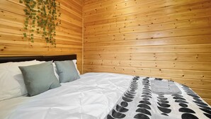 A wooden-paneled room with a bed, pillows, and a blanket.