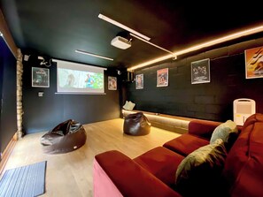 A cozy room with a projector screen, bean bags, a red couch, and wall art.