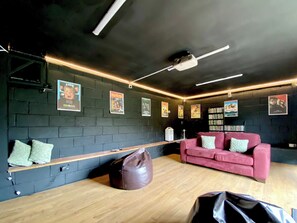 A room with a dark brick wall, a wooden bench, a red couch, and a projector on the ceiling. - Magnolia Lodge-UK46280 (Camerton, near Bath)