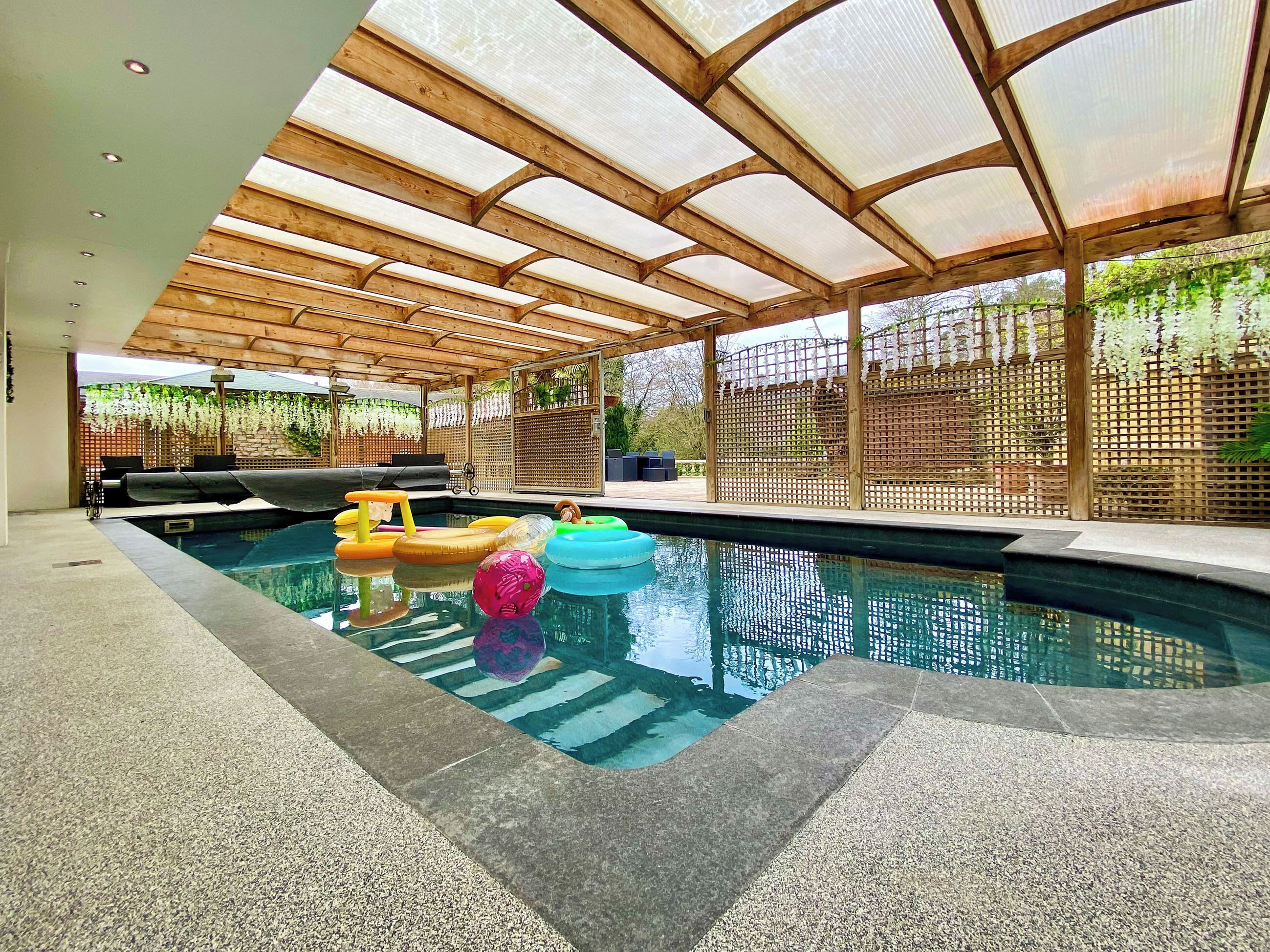 An indoor swimming pool with a wooden ceiling and a glass enclosure.