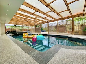 An indoor swimming pool with a wooden ceiling and a glass enclosure.