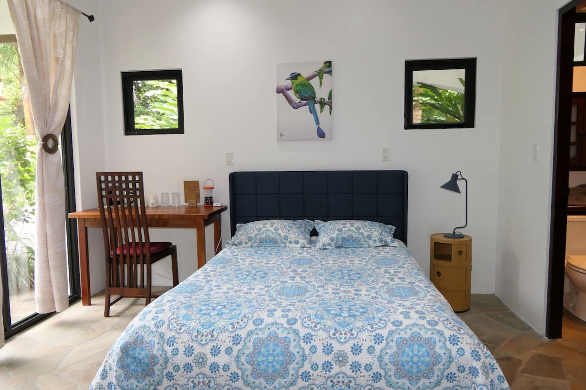 Un dormitorio con una cama, un escritorio, una silla y dos cuadros en la pared.