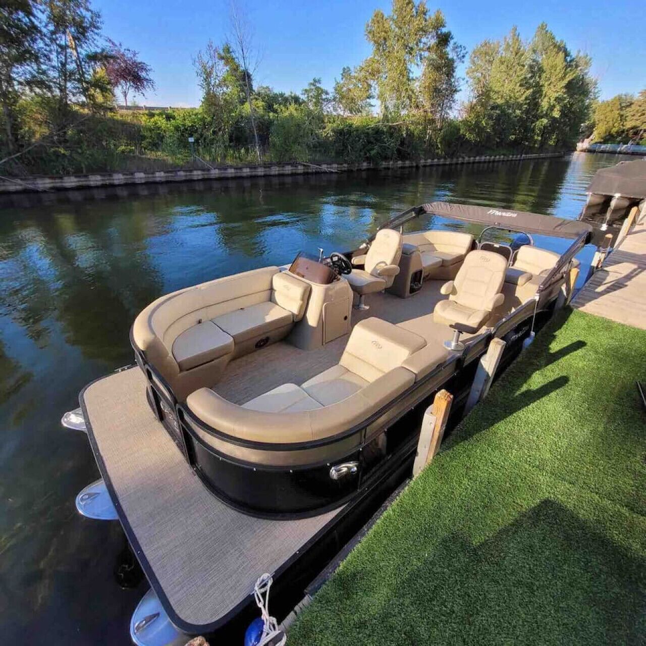 A motorboat docked at a marina with a covered seating area and a small table.