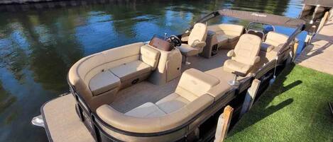 A motorboat docked at a marina with a covered seating area and a small table.
