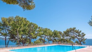 En swimmingpool med fri utsikt över havet och träd i bakgrunden.