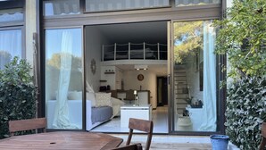 Ett modernt hus med ett rymligt vardagsrum, en matplats med ett träbord och stolar samt en stor skjutdörr i glas som leder ut till en balkong.
