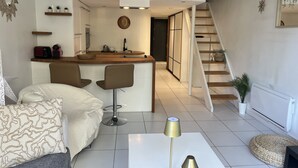 En modern lägenhet i loftstil med kök, matplats och en trappa som leder upp till en sovplats i loftet.